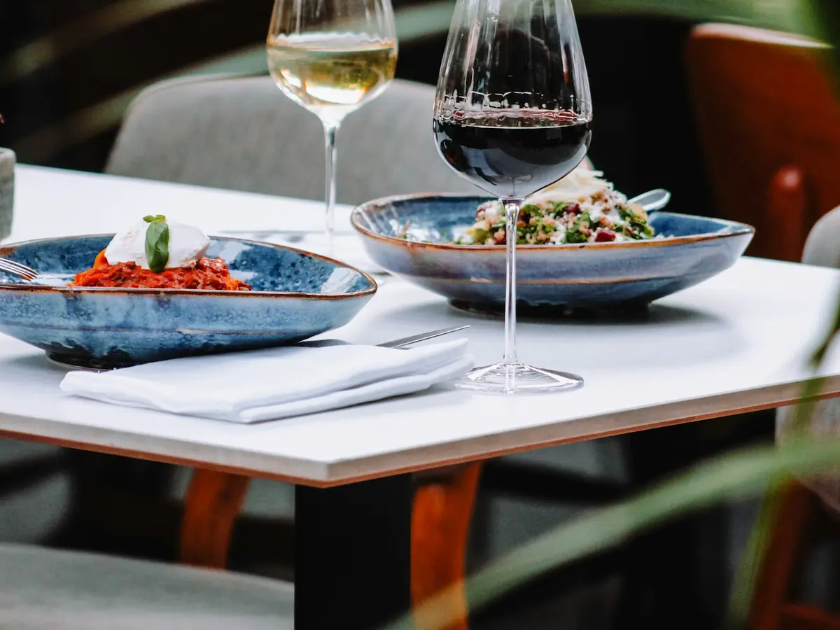 Foto de ejemplo: mesa de un restaurante con platos y copas, en una terraza.